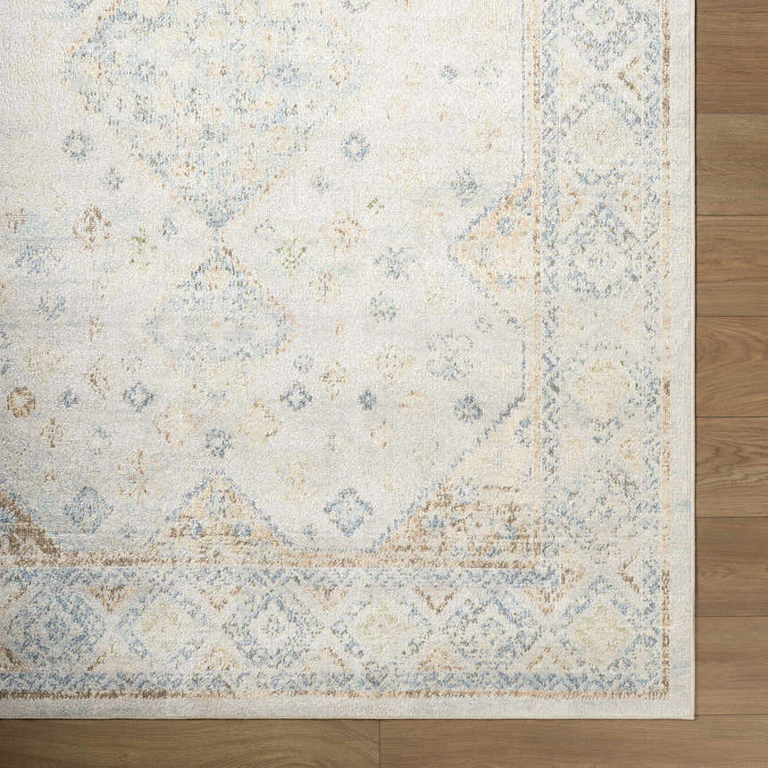 Close up of the Bhavya Cream Washable Area Rug, featuring a traditional beige, muted blue, and sage pattern. Corner