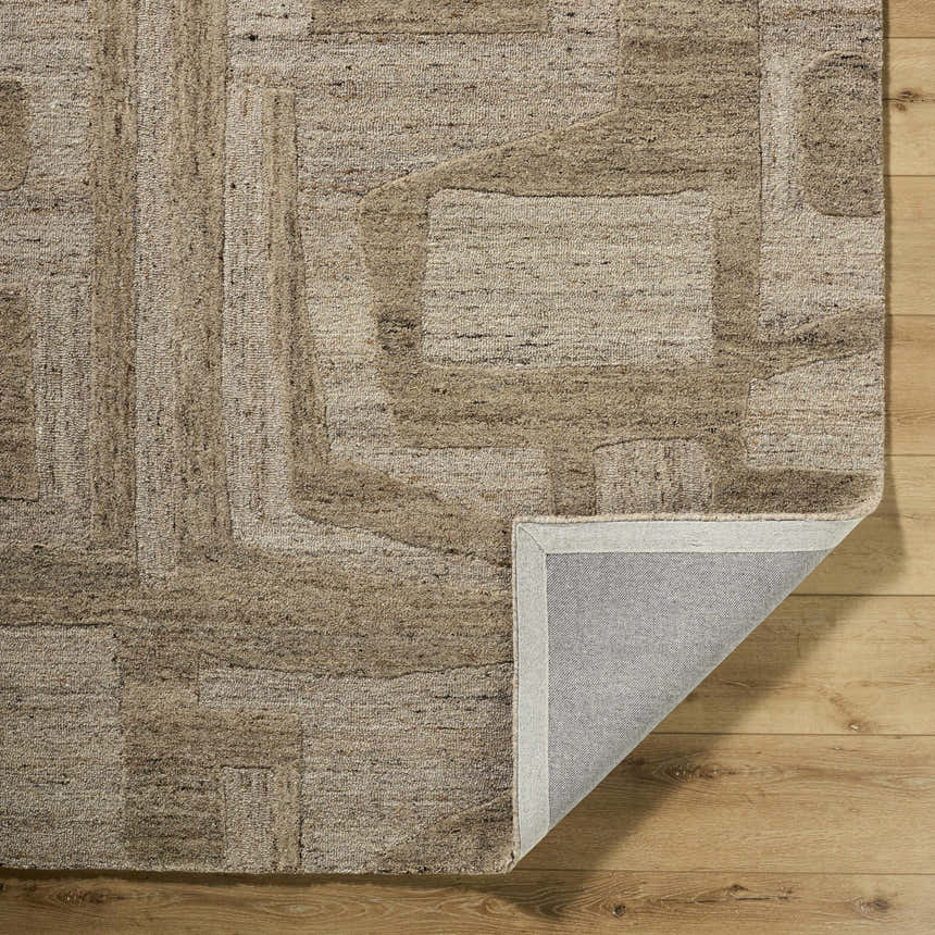 Close-up of the Brasen Tan Area Rug showing its beige, tan, and taupe geometric pattern and hand-tufted wool texture. Fold