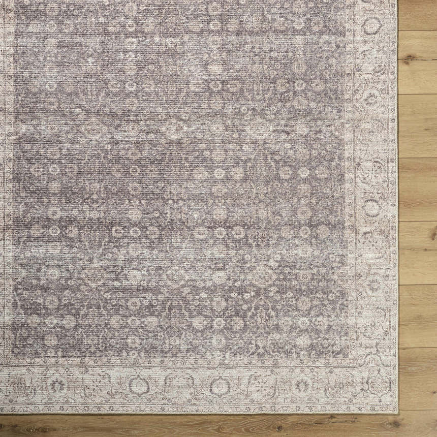 Close-up of Spokane Machine Woven rug. Beige, cream, and brown traditional pattern with a detailed border on wood floors. Corner
