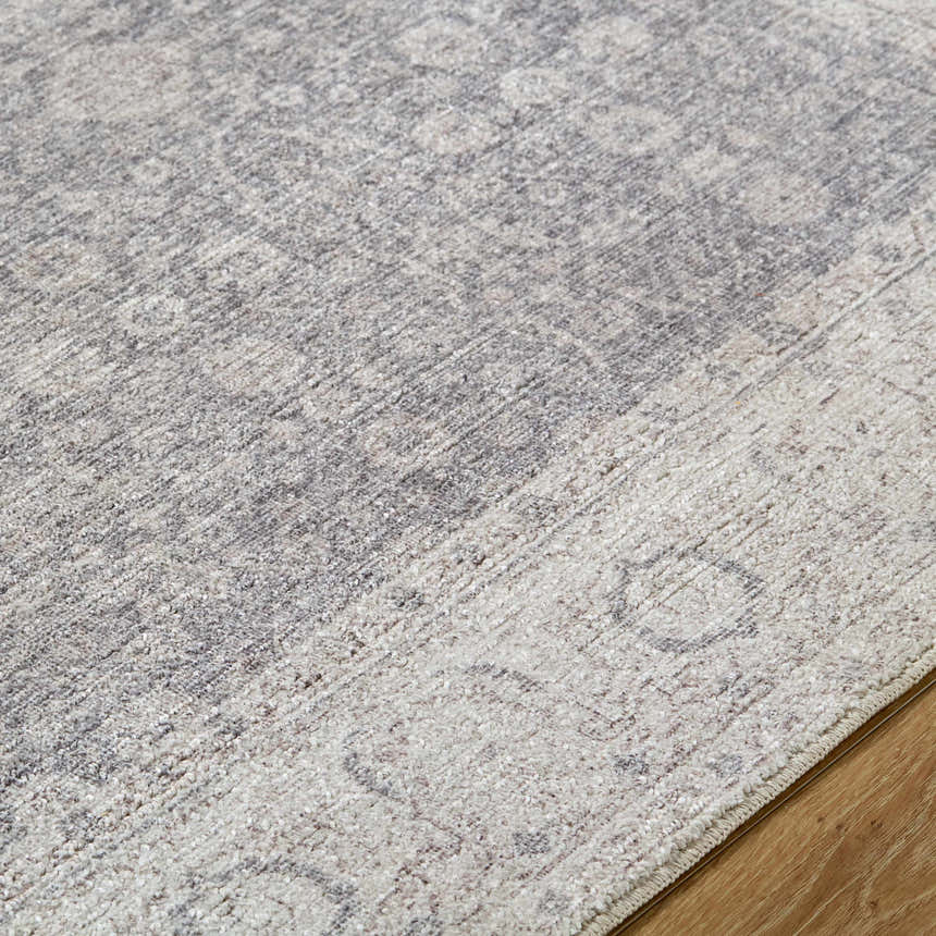 Close-up of the Spokane Machine Woven rug. Features a traditional pattern in charcoal, dark brown, and off-white. Texture