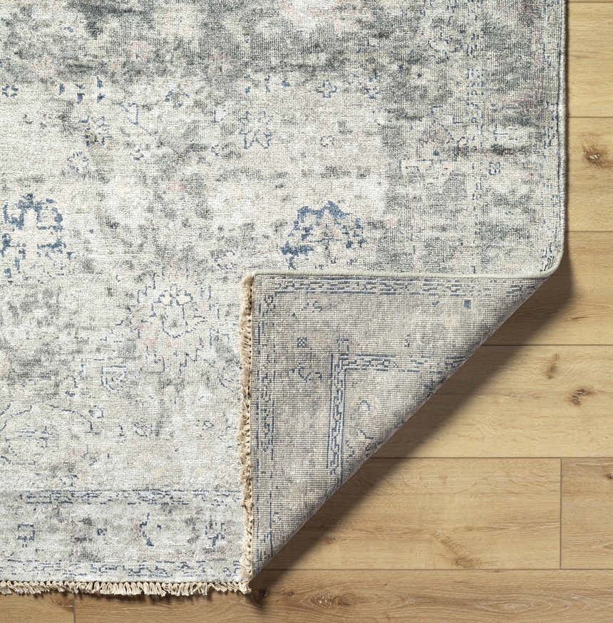 Close-up of the Ballantrae Premium Rug showing the beige, gray, and blue traditional hand-knotted design and viscose texture. Fold
