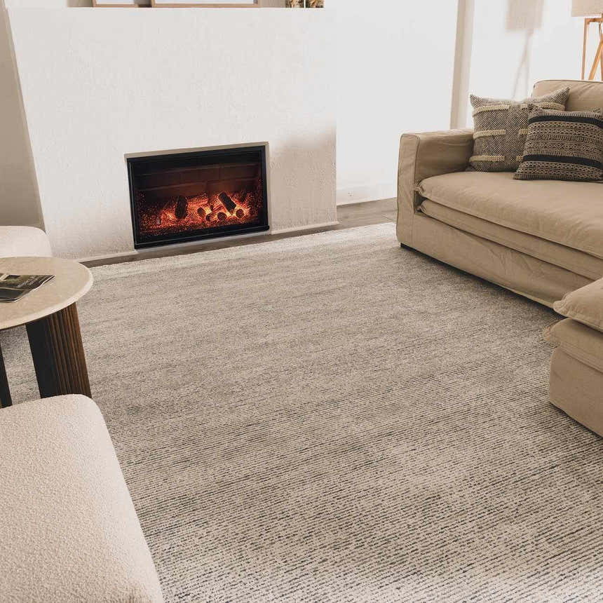 Living room scene with a slate Orcas Hand Tufted Wool-Blend Rug, beige sofa, fireplace, and neutral tones for a cozy, modern look. Roomscene-Rectangle
