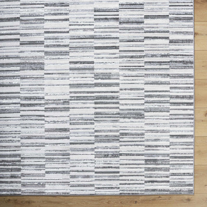Close-up of Bronco Broken Striped Area Rug. Contemporary design with black, charcoal, gray, and ivory stripes. Corner