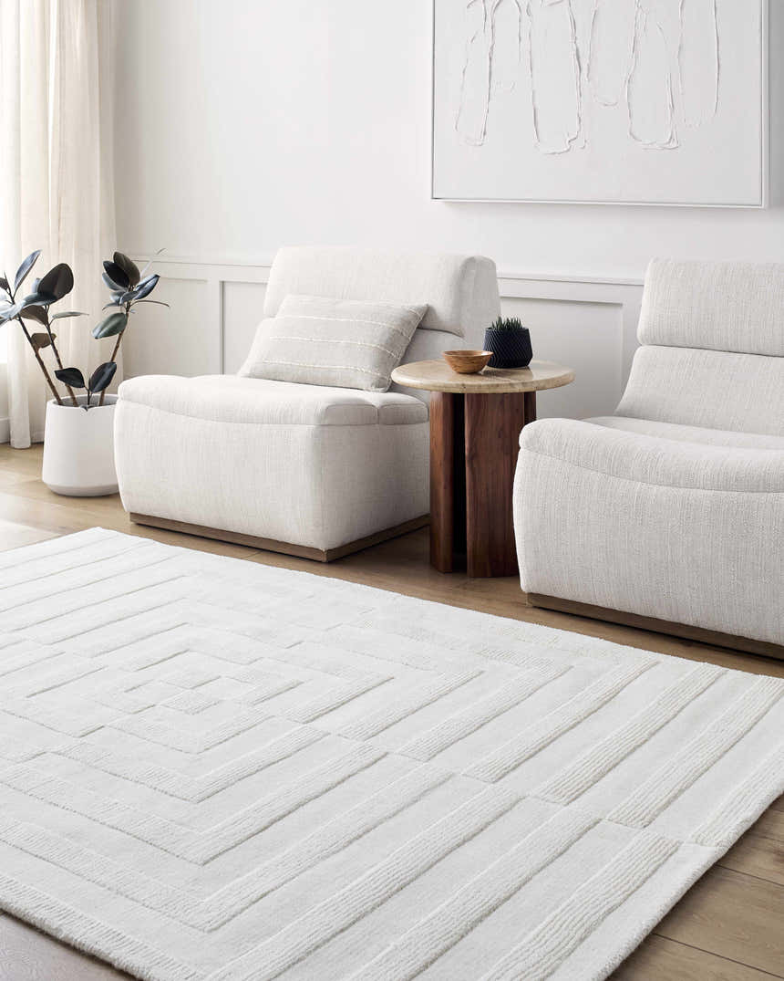 Minimalist living room with cream Armina Area Rug, two chairs, wood side table, and neutral artwork. Roomscene-Rectangle