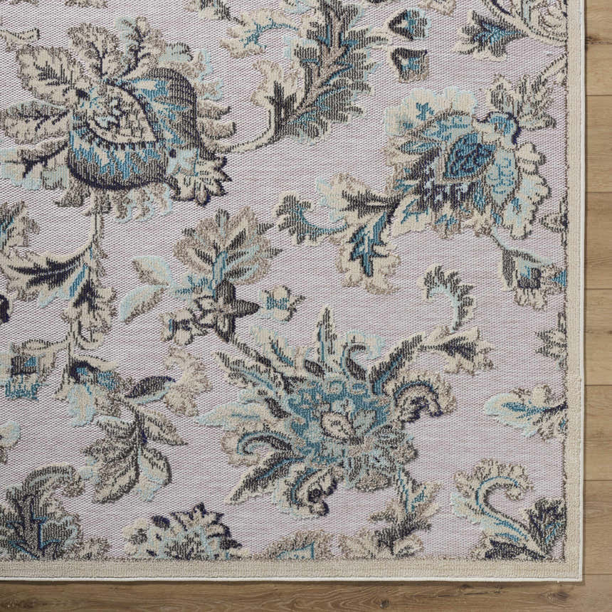 Close-up of the Benita Area Rug. Coastal style with aqua, cream, and light brown floral pattern. Machine woven polypropylene texture. Corner