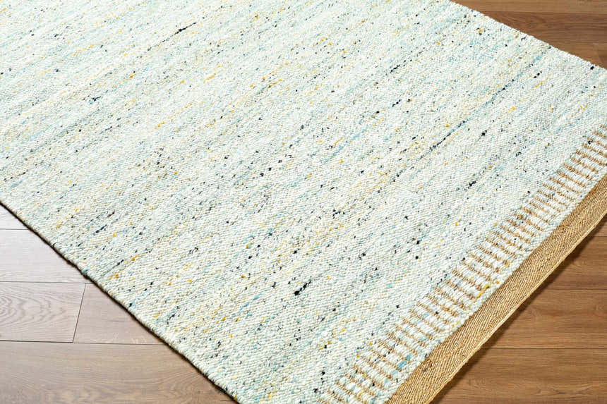 Close-up of the hand woven Andrey Dark Beige Area Rug showing texture, charcoal, light and medium brown colors. Corner