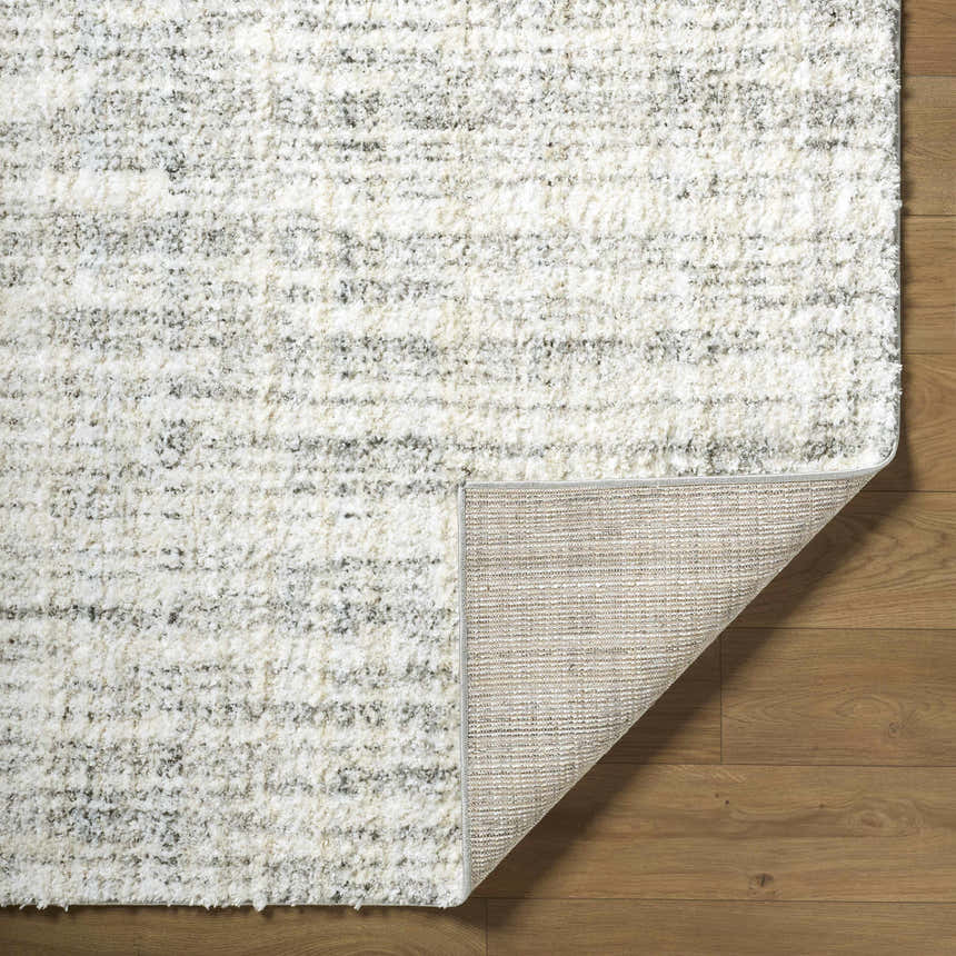 Close-up of the textured Yidia White area rug showing off-white, light gray, and black tones. Fold