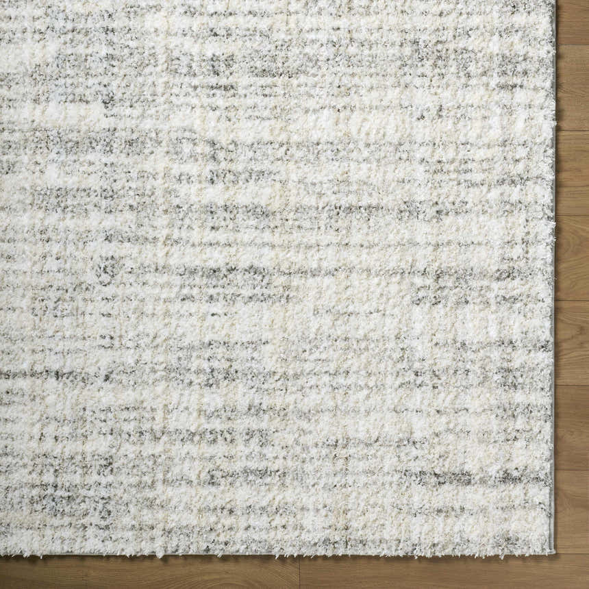 Close-up of the Yidia White rug, a machine-woven polyester rug with off-white, light gray, and black horizontal striations. Corner