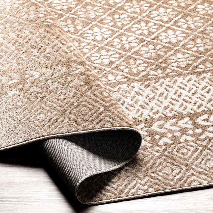 Close-up of the Caditaan Washable Area Rug. Brown and cream floral geometric pattern. Machine woven polyester rug. Fold