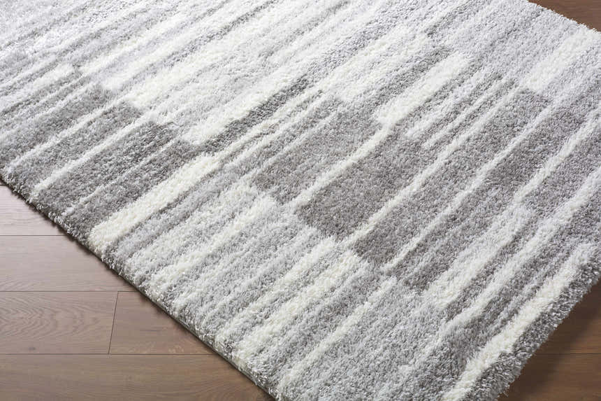 Close-up of the shaggy Carlen Gray Area Rug, with a contemporary gray and ivory striped pattern. Corner