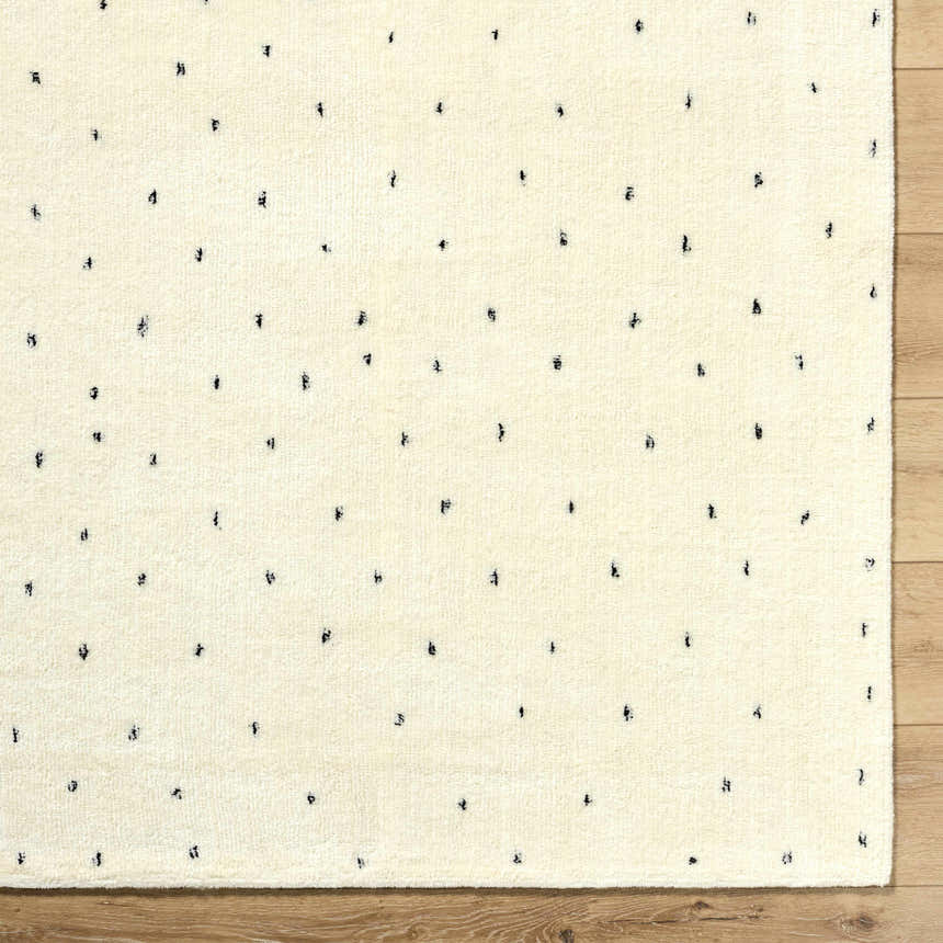 Close-up of the ivory Cirila Dotted Wool Rug showing the charcoal dots and soft, hand-tufted wool texture. Swatch
