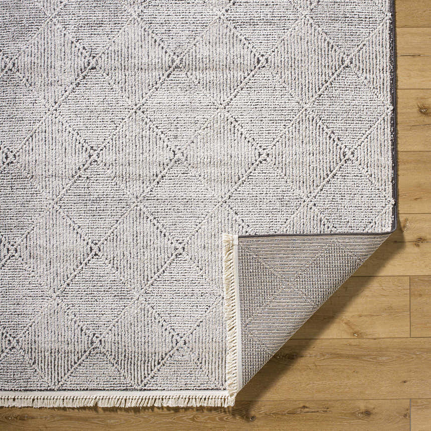 Close-up of Cannan Area Rug, ivory and black geometric design, machine woven texture, fringe detail. Fold