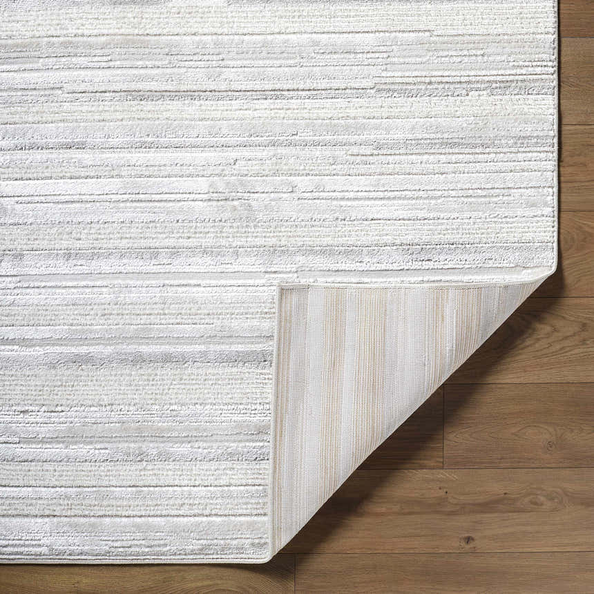 Close-up of the Cardea Area Rug showing its cream, ivory, and gray horizontal stripes and the rug's backing. Fold