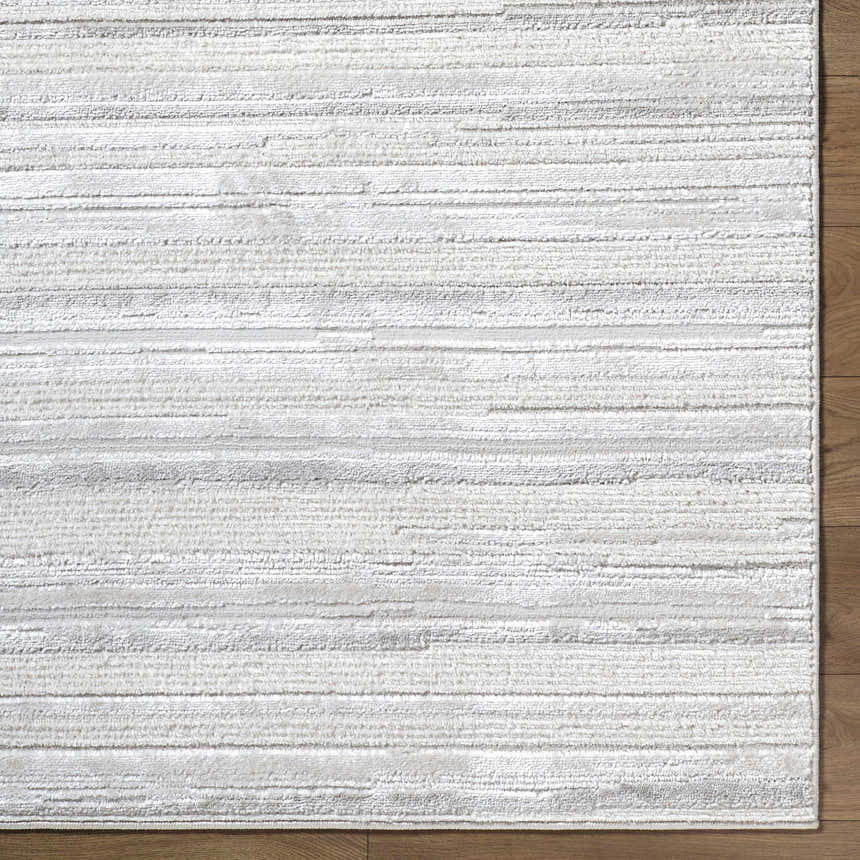 Close-up of the Cardea Area Rug. Cream, ivory, light gray, and white horizontal stripes on a textured, machine-woven rug. Corner