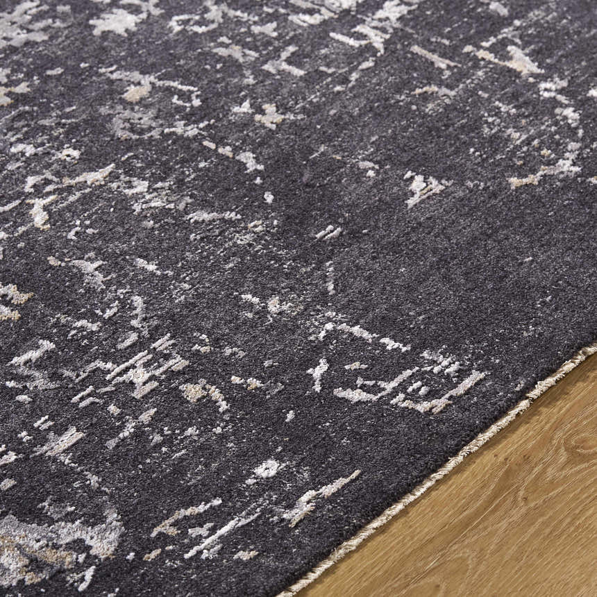 Close up of the Corina Black Area Rug showing its charcoal, gray, and ivory abstract pattern and soft texture. Texture