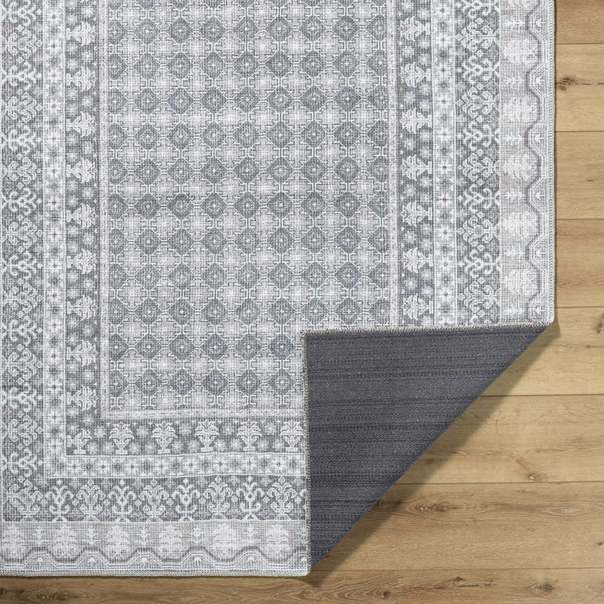 Close-up of the Rainier PNW Home x LIVABLISS rug. Machine woven rug in off-white, pale blue, sage, and tan with traditional patterns. Fold