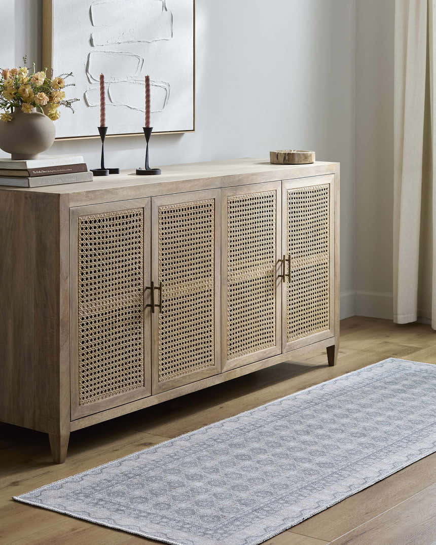 Living room scene with a Rainier rug runner in pale blue, styled under a wooden cabinet with woven door panels. Roomscene-Runner