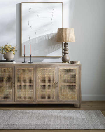 Living room scene with a Spokane Machine Woven rug, wood cabinet, lamp, and abstract art. Neutral colors create a calming mood. Roomscene-Rectangle