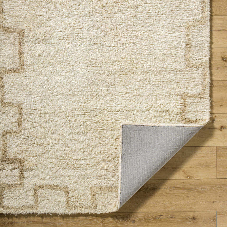 Close-up of the Ciniod Area Rug showing its tan geometric pattern, wool texture, and gray backing on wood floor. Fold