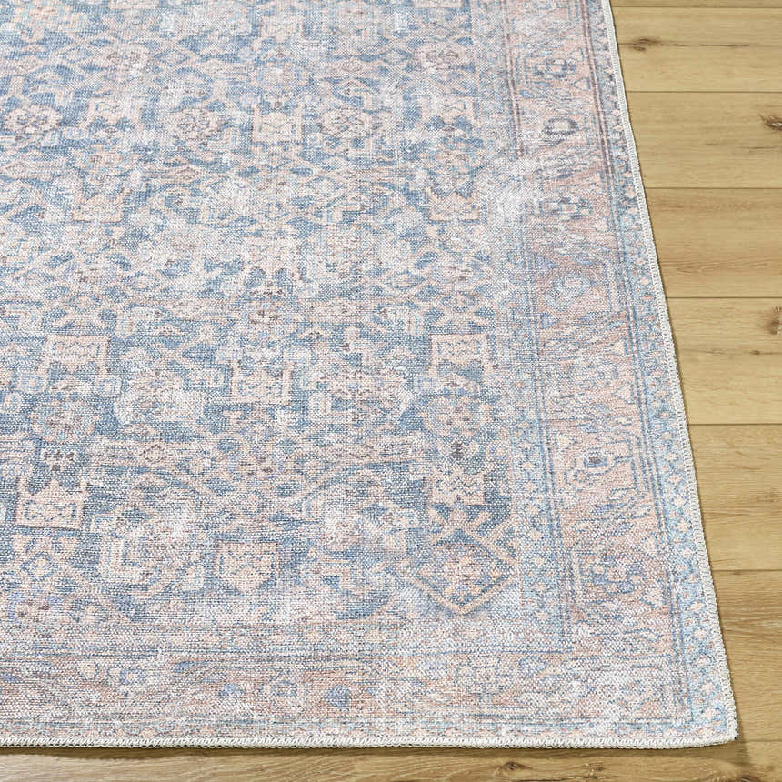 Close-up of the Crevan Washable Area Rug showing its traditional denim, sage, and tan pattern and machine-woven texture. Front