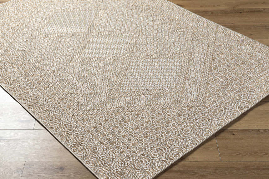 Close-up of the tan and white geometric patterned Chaman Area Rug on a wood floor. Corner