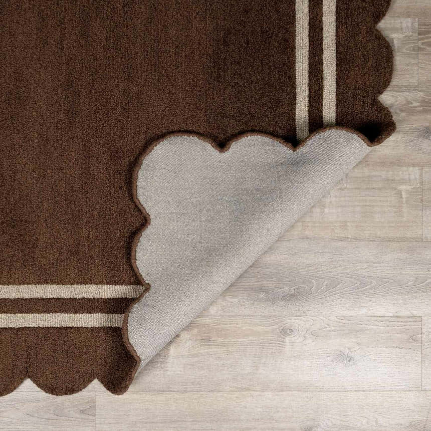 Close-up of the hand-tufted Chogan Chocolate Brown Area Rug with a scalloped edge and two beige stripes. Wool texture. Fold