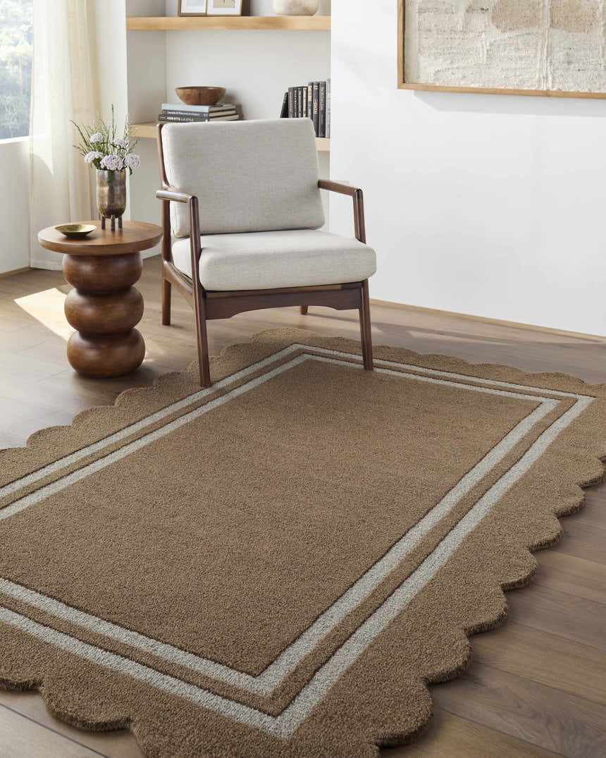 Living room scene with a Chogan Umber Area Rug. The rug is wool, brown with scalloped edges, and sits under a chair and side table. Roomscene-Rectangle