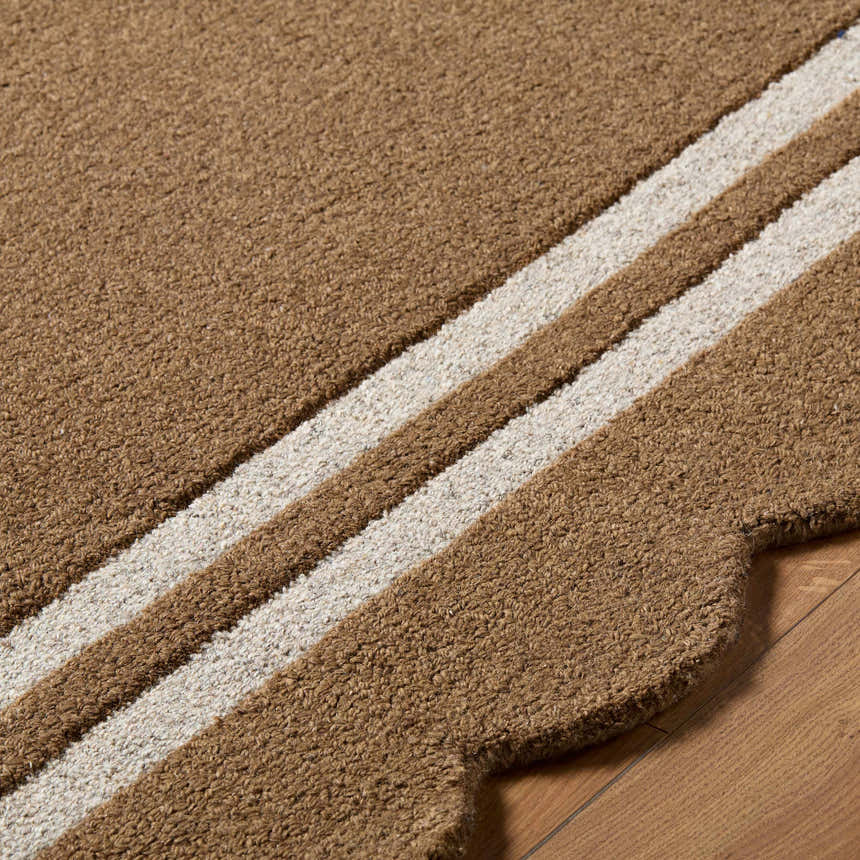Close-up of the hand-tufted Chogan Umber Area Rug, showing umber and cream stripes and scalloped edge detail. Texture