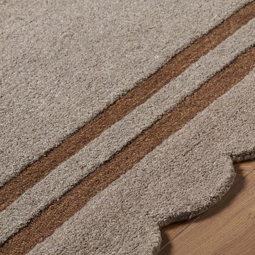 Close-up of the hand-tufted Chogan Charcoal Area Rug showing texture and brown stripes on a wood floor. Texture