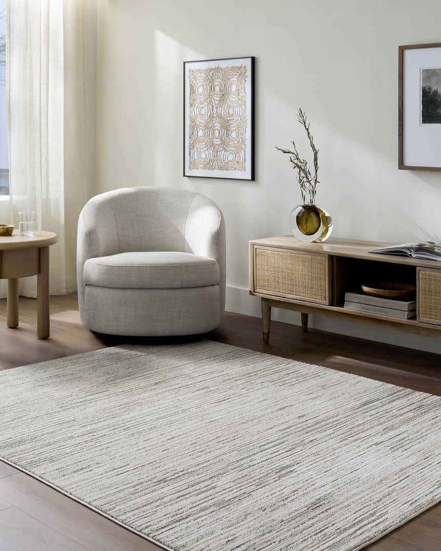 Living room scene with a cream armchair and the Corwin 3D Striped Washable Area Rug in cream, gray, and sage. Roomscene-Rectangle