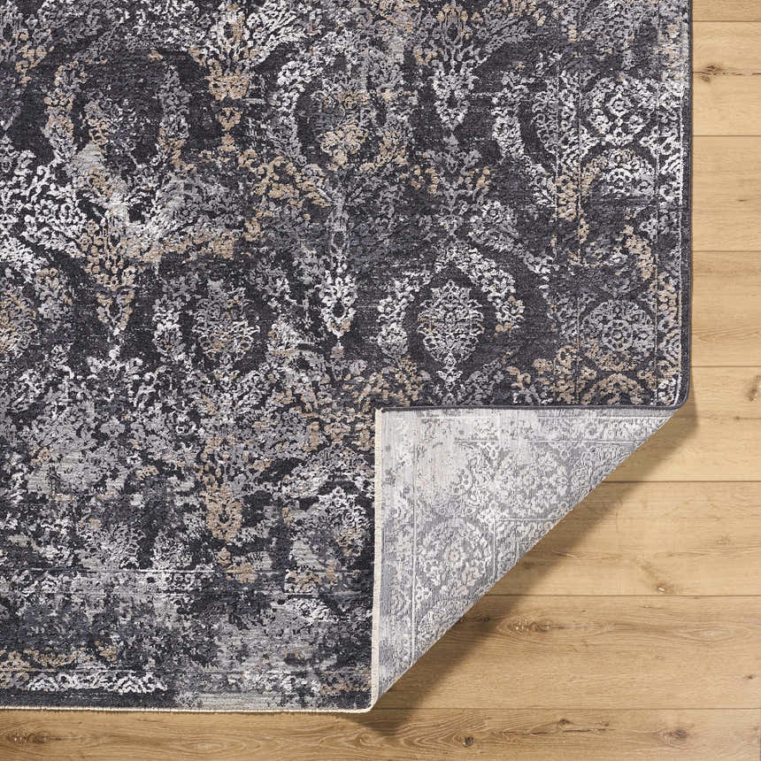Close-up of the Alexei Area Rug, a machine-woven rug in black, charcoal, gray, and tan with a traditional floral pattern. Fold