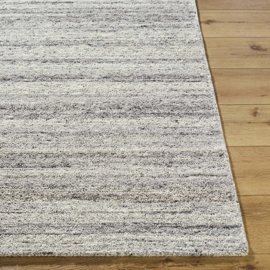 Close-up of the hand-tufted Capote Stone Gray Area Rug. Ash, charcoal, and ivory wool rug with a subtle horizontal stripe design. Front