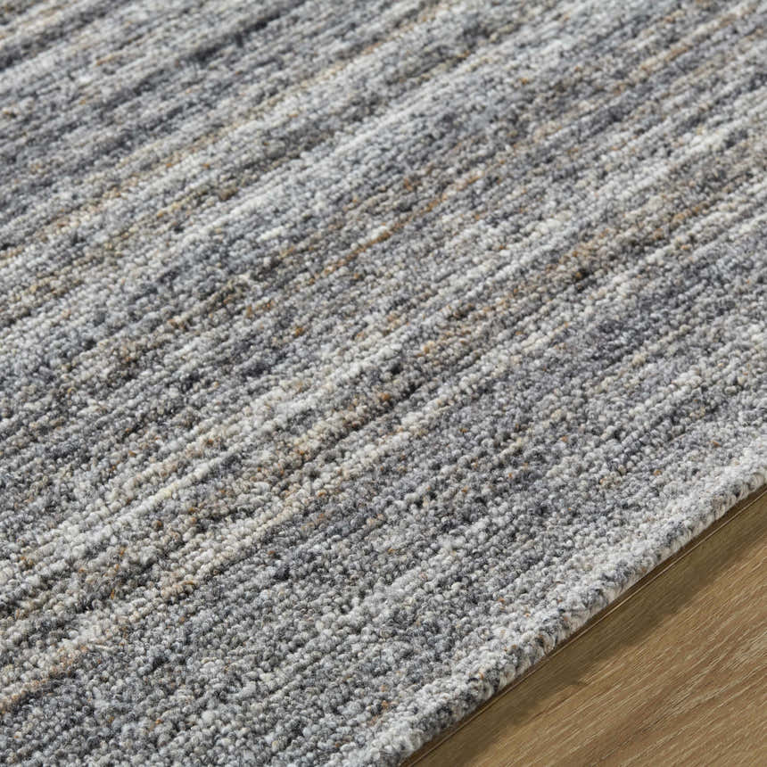 Close-up of the hand-tufted Capote Tan Area Rug showing its ash, charcoal, and tan tones and textured wool design. Texture