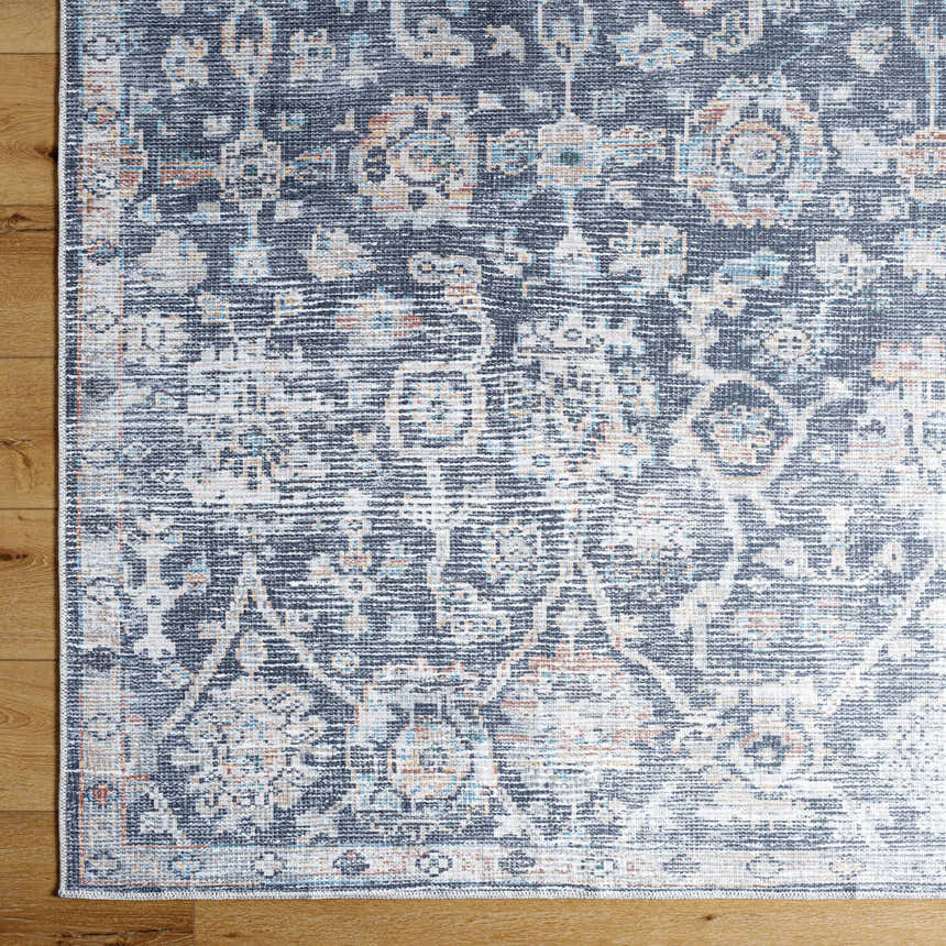 Close-up of the Eleni Vivir x LIVABLISS washable area rug. Features a traditional beige, black, and denim pattern. Swatch