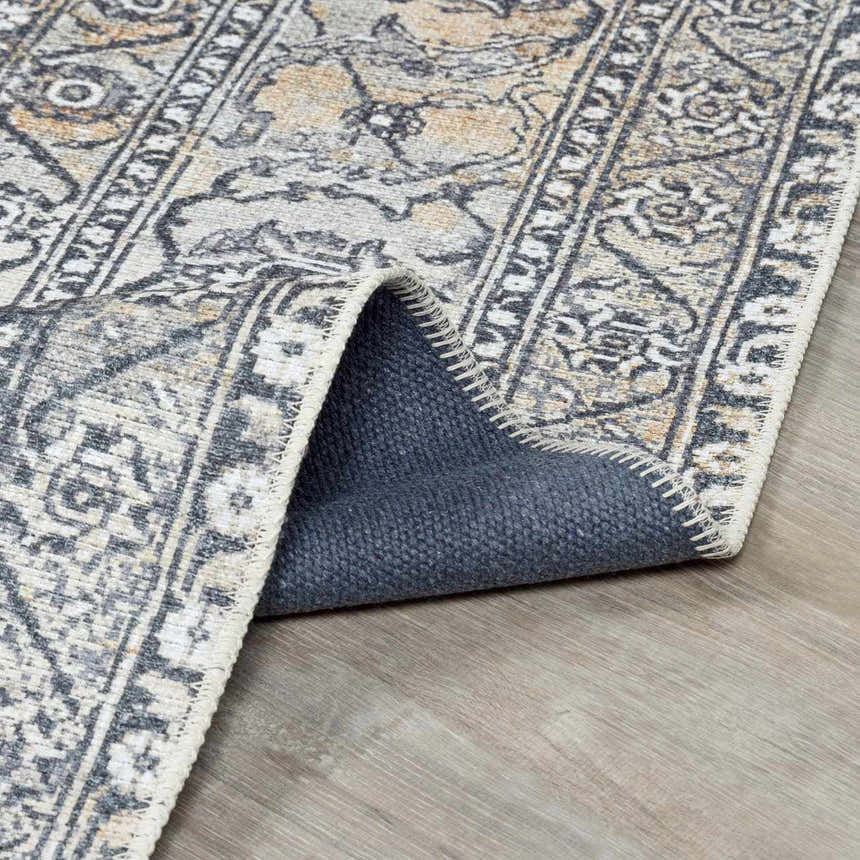 Close-up of the Dagatan Washable Area Rug showing its beige, black, and gray traditional pattern and durable construction. Fold