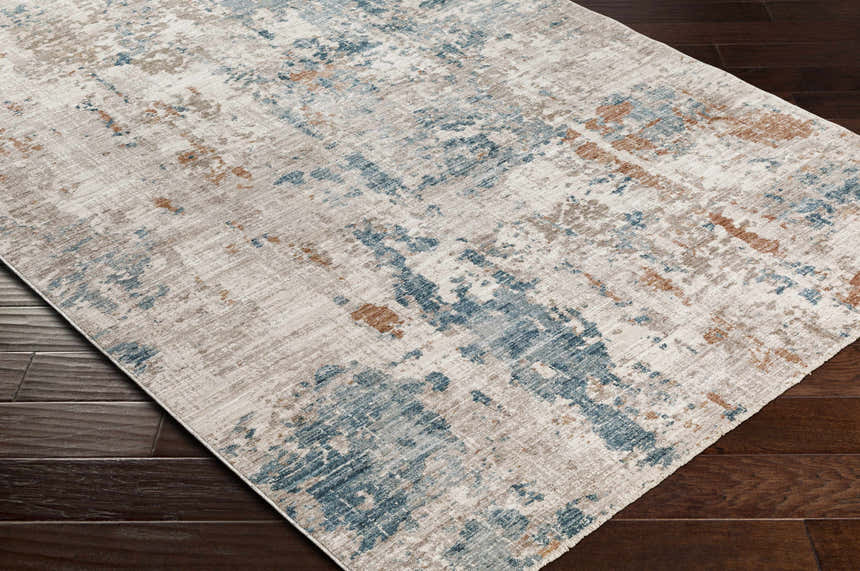 Close-up of the Danlugan Area Rug. Contemporary style with charcoal, cream, dusty pink, medium brown, and pale blue colors. Corner