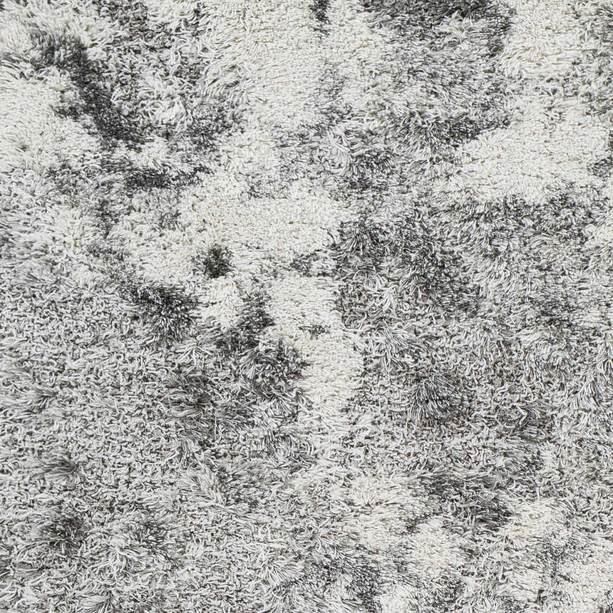 Close-up of the Livabliss Alta Shag rug. Gray, light gray, and off-white tones create a soft, textured shag design. Texture