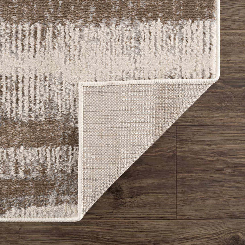 Close-up of the Asmara Brown Area Rug showing its textured stripes and backing on dark wood flooring. Fold