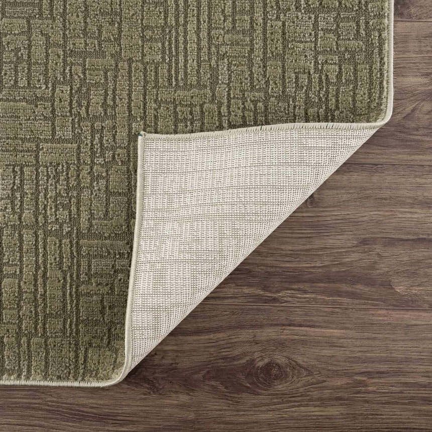 Close-up of the Leanna Green Washable Area Rug showing its geometric design, texture, backing, and green color. Fold