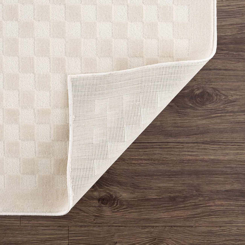 Close-up of the Gaiwan Cream Washable Area Rug showing its cream checkerboard design, texture, and non-slip backing. Fold