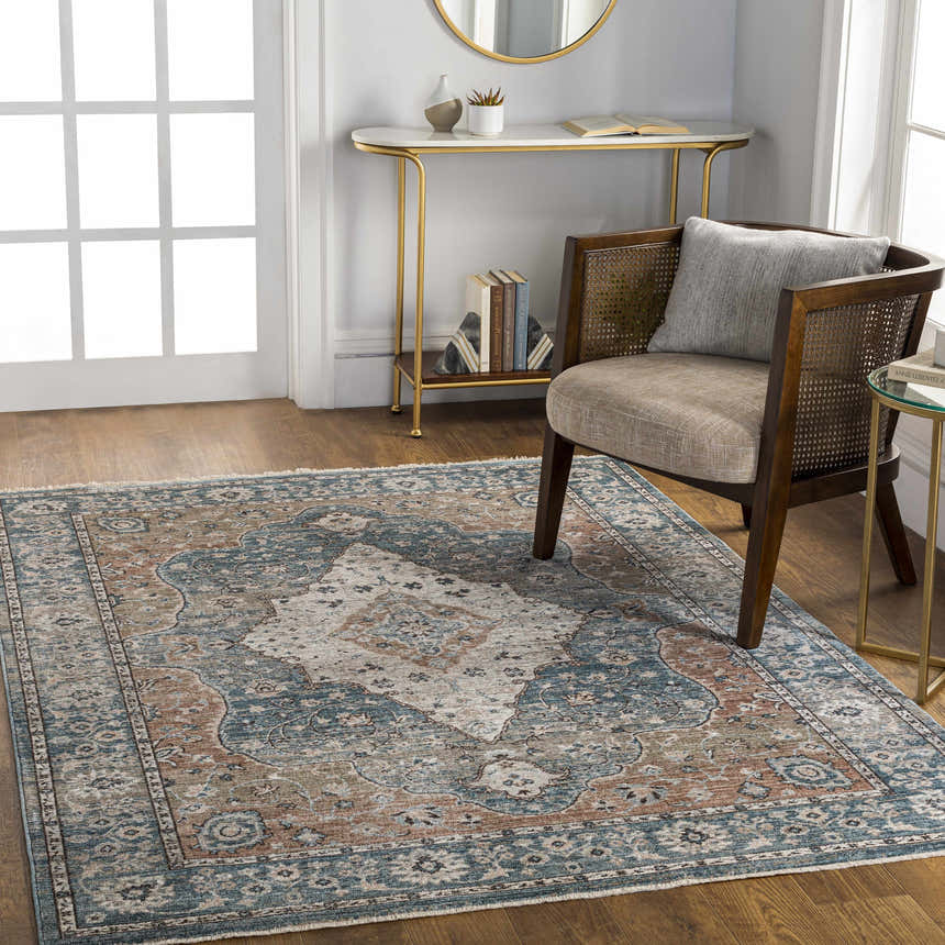 Living room scene with the Edremit Area Rug in cream, blue, and brown, styled with a wood chair and gold accent tables. Roomscene-Rectangle