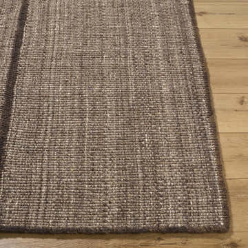 Close-up of the hand woven texture of the Lisua Global Modern Wool Area Rug in neutral brown tones on wood floor. Front