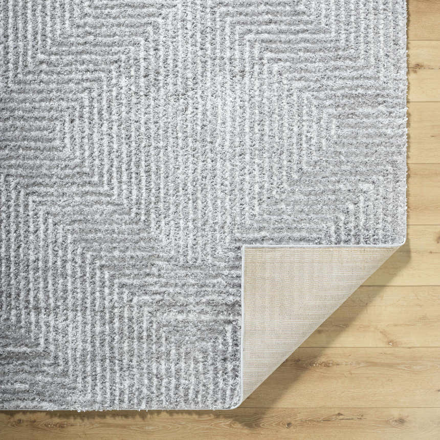Close-up of the Ashlyn Gray Area Rug showing its light slate color, shag texture, and geometric pattern. Fold