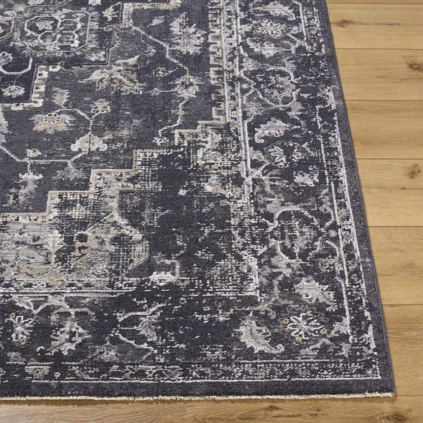 Close-up of the Alissa Black Area Rug. Traditional design in black, charcoal, gray, and ivory on a wood floor. Front