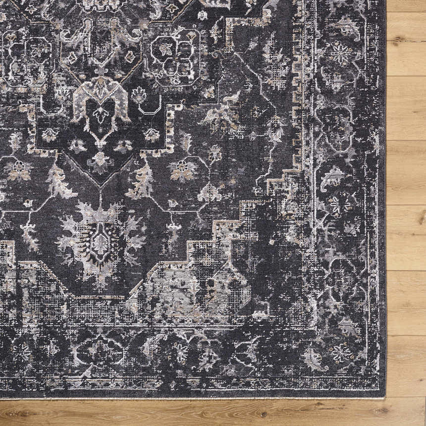Close-up of the Alissa Black Area Rug showing its traditional, distressed black, gray, and ivory pattern on wood floor. Corner