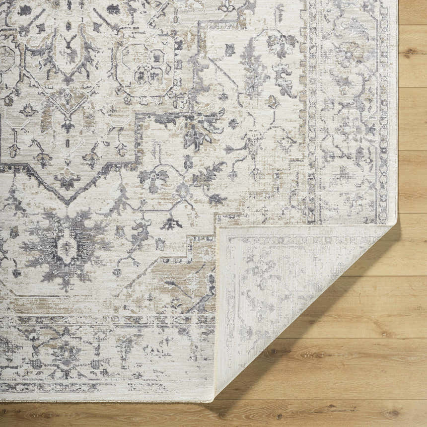 Close-up of the Alissa Cream Area Rug showing its traditional charcoal, gray, and tan floral pattern and folded corner. Fold