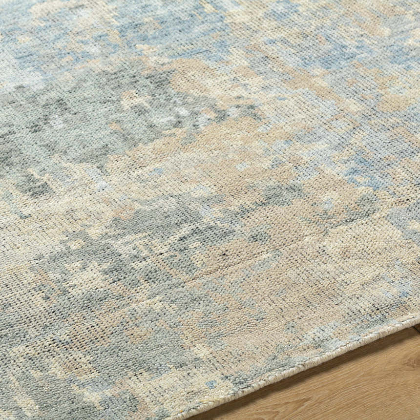 Close-up of the Greenhills Handmade Wool Area Rug. Abstract pattern in beige, charcoal, and denim. Hand-knotted texture. Texture