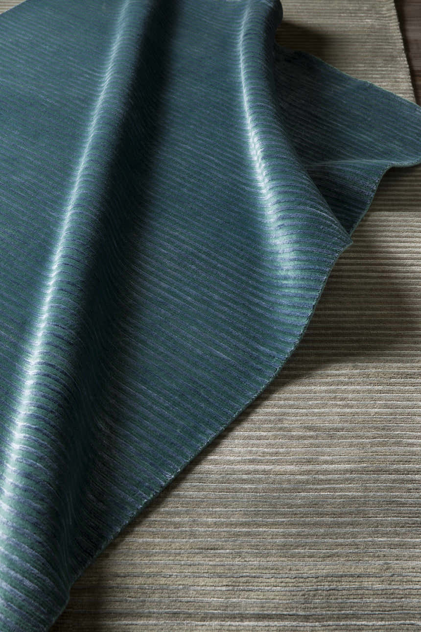 Close-up of the teal and dark blue striped texture of the Guyton Area Carpet. Styleshot