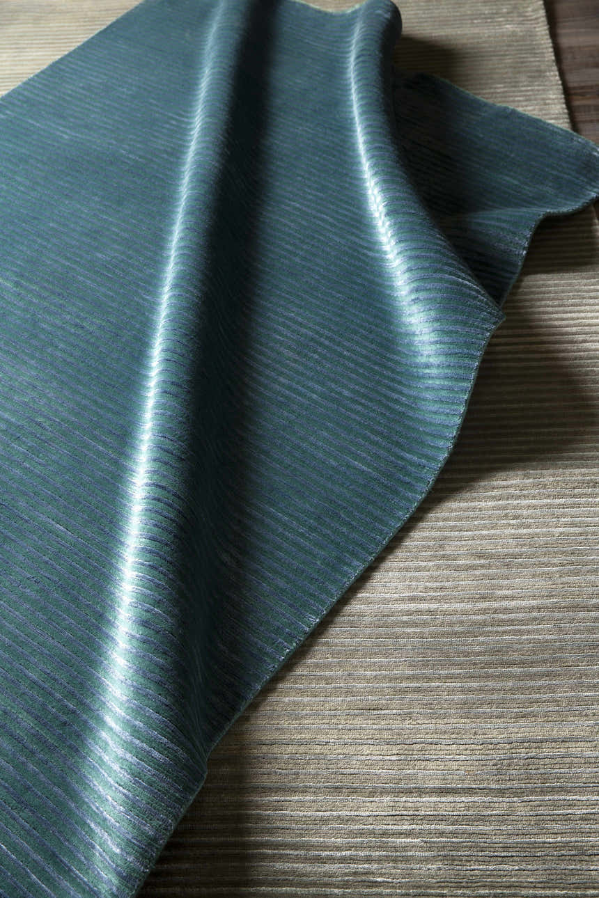 Close-up of the teal and dark blue Guyton Area Carpet showing its hand-knotted texture and striped pattern. Styleshot