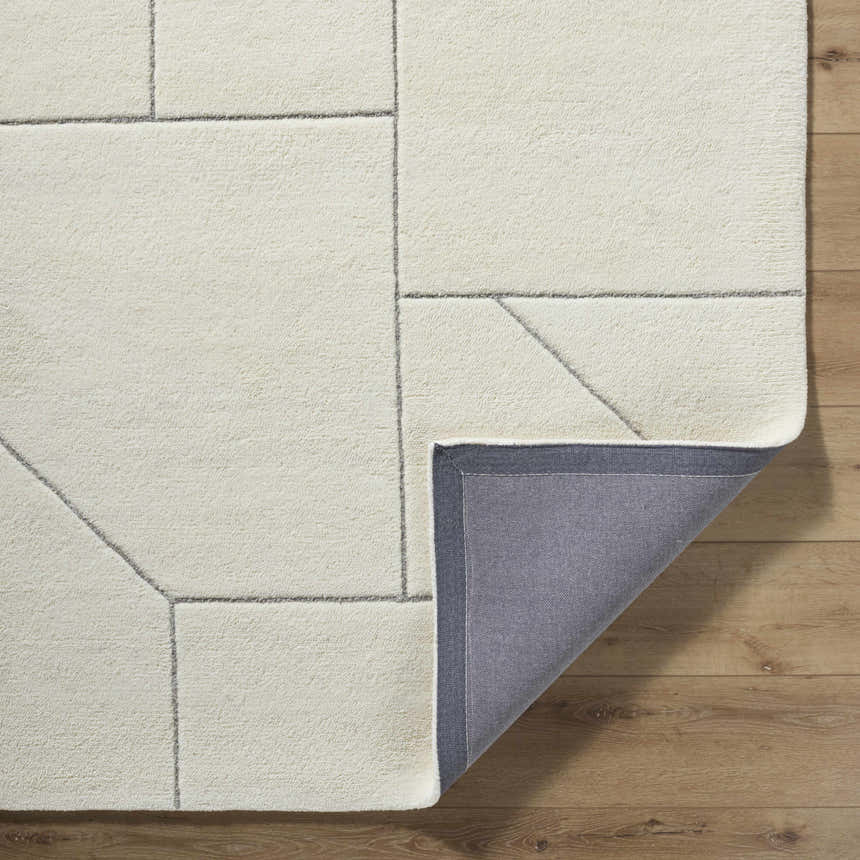 Close up of the Alaina Area Rug showing its ivory wool texture and charcoal geometric pattern. Fold